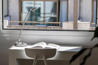 a desk with a lamp and a book and a chair at Bright Apartment in the Heart of Cannes in Cannes