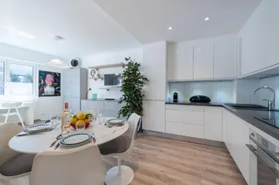 a kitchen with white cabinets and a table and chairs at Bright Apartment in the Heart of Cannes in Cannes