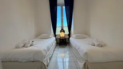 two beds in a room with a window at Reine des Mers in Cannes