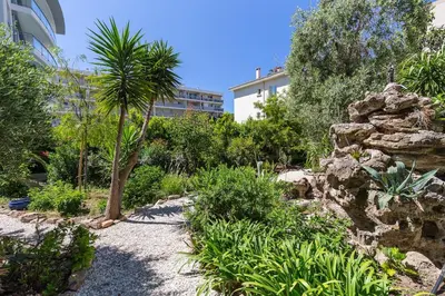 a garden with a palm tree and a rock at Reine des Mers in Cannes