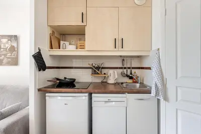 a small kitchen with white cabinets and a sink at Apartment with Garden, Pool, Sea View and Parking in Cannes