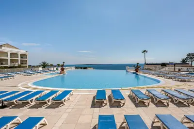 a large swimming pool with lounge chairs and the ocean at Apartment with Garden, Pool, Sea View and Parking in Cannes