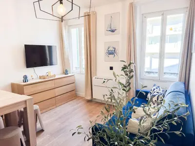 a living room with a blue couch and a tv at Suite Palmiers bleus Cannes in Cannes