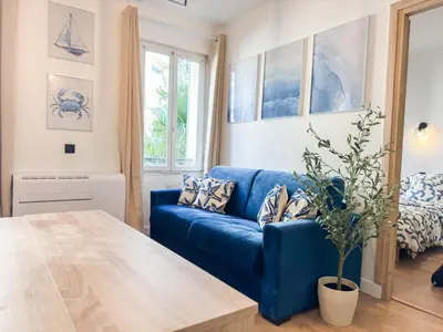 a blue couch in a living room with a table at Suite Palmiers bleus Cannes in Cannes