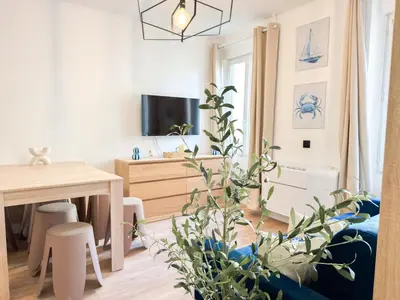 a living room with a table and a desk with a plant at Suite Palmiers bleus Cannes in Cannes