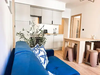 a living room with a blue couch and a kitchen at Suite Palmiers bleus Cannes in Cannes