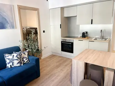 a living room with a blue couch and a kitchen at Suite Palmiers bleus Cannes in Cannes