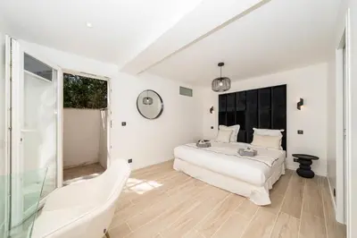 a white bedroom with a bed and a window at One of a kind 6 BR 6 bath villa sauna jacuzzi pool just 15 mns off town in Cannes