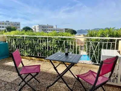 a black table and two pink chairs on a balcony at Holidays in Cannes