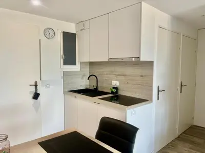 a kitchen with white cabinets and a sink and a black chair at Holidays in Cannes