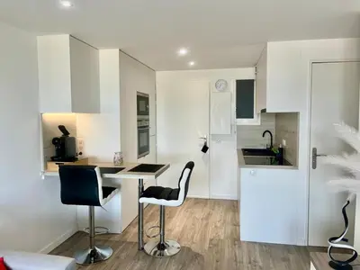 a white kitchen with a counter and two stools at Holidays in Cannes