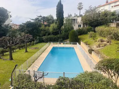 a large swimming pool in a yard with trees at Light modern Studio with Garden terrace shared pool - 2294 in Cannes