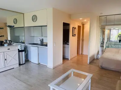 a kitchen and living room with white cabinets and a bed at Light modern Studio with Garden terrace shared pool - 2294 in Cannes