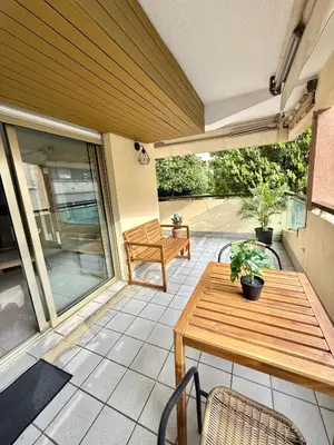 a patio with a wooden table and chairs at Appartement cosy avec terrasse, proche plages & Palais in Cannes