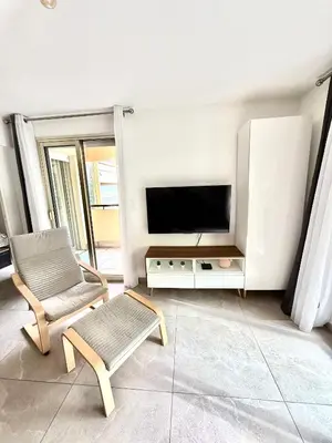 a living room with a television and two chairs at Appartement cosy avec terrasse, proche plages & Palais in Cannes