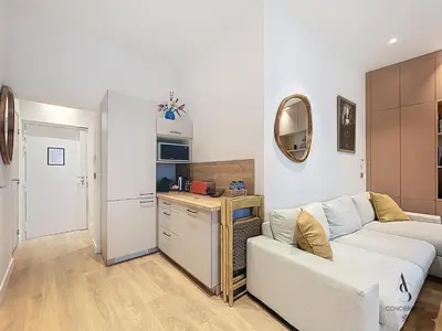 a living room with a couch and a kitchen at Le Forville - 2 chambres - 5 min Palais - Suquet in Cannes