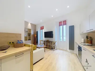 a kitchen and living room with a couch and a table at Le Forville - 2 chambres - 5 min Palais - Suquet in Cannes