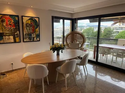 a dining room with a wooden table and chairs at Appt 2ch 90m2 avec terrasse 40m2, piscine et tennis in Cannes