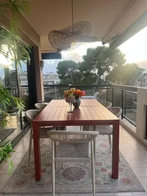 a wooden table with a vase of flowers on a balcony at Appt 2ch 90m2 avec terrasse 40m2, piscine et tennis in Cannes