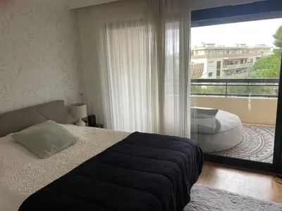 a bedroom with a bed and a large window at Appt 2ch 90m2 avec terrasse 40m2, piscine et tennis in Cannes