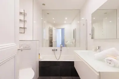 a white bathroom with a tub and a sink at Immogroom - Renovated & Cozy One-Bedroom Flat in Cannes