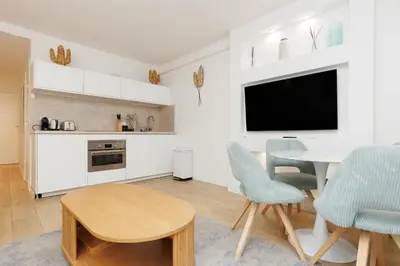 a white kitchen with a table and chairs and a tv at El Sole - Plage - Wifi - Croisette in Cannes