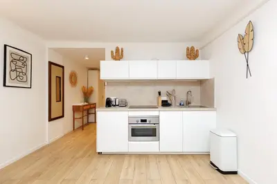 a kitchen with white cabinets and a hardwood floor at El Sole - Plage - Wifi - Croisette in Cannes