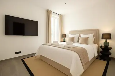 a white bedroom with a large bed with a flat screen tv at French Dolce Vita near Croisette in Cannes