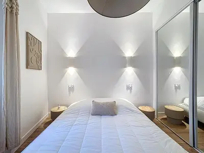 a bedroom with a large bed with lights on the wall at Effet Mer - neuf, central, Port, Plage&Palais, clim in Cannes