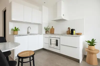 a kitchen with white cabinets and a table at Seaview Studio, Palais des Festivals in Cannes