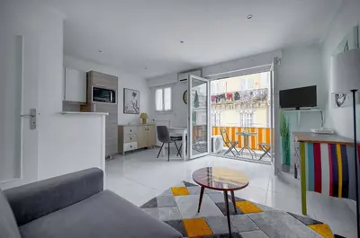 a living room with a table and a kitchen at Studio lumineux avec balcon A0B207 in Cannes