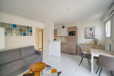 a living room with a couch and a table and a kitchen at Studio lumineux avec balcon A0B207 in Cannes