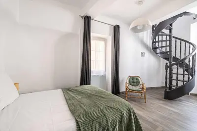 a bedroom with a bed and a spiral staircase at LA MAISON DU SUQUET duplex avec terrasse en plein centre in Cannes