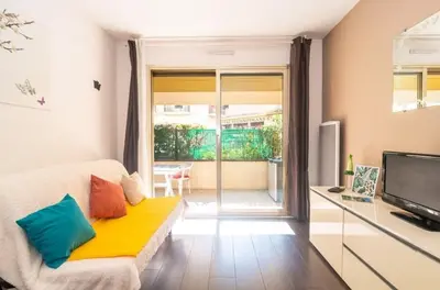 a living room with a couch and a television at Pause Riviera avec terrasse, à 300 mètres de la mer in Cannes