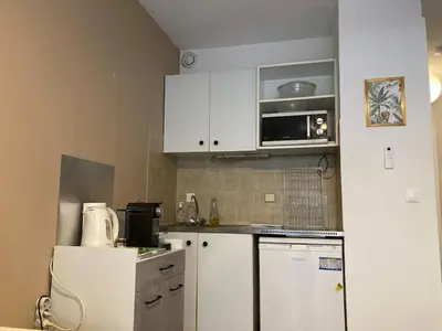 a small kitchen with white cabinets and a refrigerator at Pause Riviera avec terrasse, à 300 mètres de la mer in Cannes