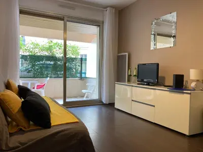 a living room with a couch and a television at Pause Riviera avec terrasse, à 300 mètres de la mer in Cannes
