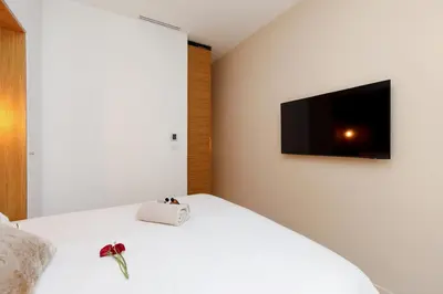 a bedroom with a white bed with a television on the wall at Modern 2 Bedroom Overlooking Cannes Old Port in Cannes