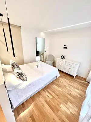 a white bedroom with a bed and a dresser at Studio La Baronne in Cannes