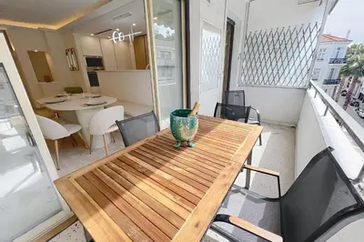 a wooden table on a balcony with chairs and a table at Wide and sunny 3 BR 2 Baths heart of Cannes gorgeous terrace city ctr in Cannes
