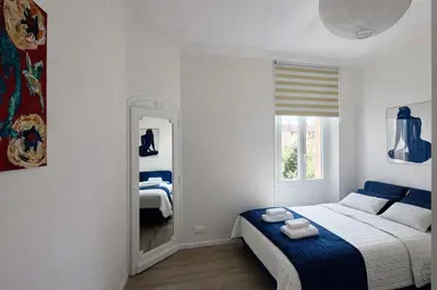 a bedroom with a blue and white bed and a mirror at Cannes Central Balcony- 9 min Festival in Cannes