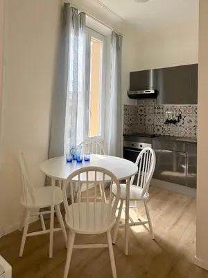 a kitchen with a white table and chairs in a room at Cannes Central Balcony- 9 min Festival in Cannes
