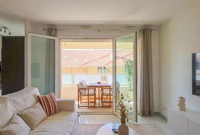 a living room with a couch and a view of a table at Apt Lumineux avec Terrasse à 5' du Centre in Cannes