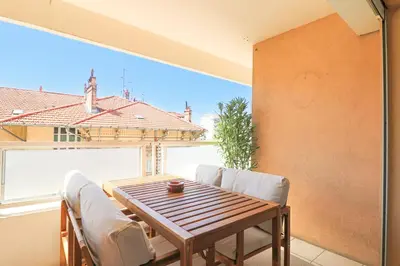 a dining room with a table and chairs and a large window at Apt Lumineux avec Terrasse à 5' du Centre in Cannes