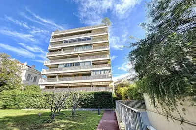 a tall apartment building with a park in front of it at Bright and vast studio terrace easy parking Cannes heart of town 1 mn in Cannes