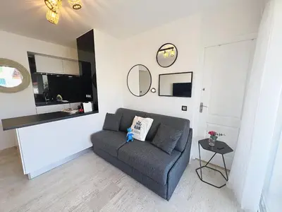 a living room with a couch and a table at Bright and vast studio terrace easy parking Cannes heart of town 1 mn in Cannes