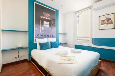 a bedroom with a large bed with a blue wall at LE MIROIR D'ANDRÉ séjour de bonheur au cœur de Cannes in Cannes