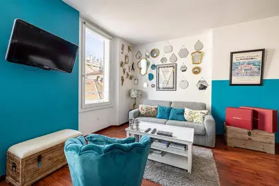 a living room with a couch and a tv at LE MIROIR D'ANDRÉ séjour de bonheur au cœur de Cannes in Cannes