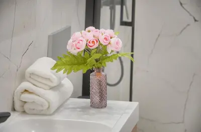 a vase of pink roses sitting on a bathroom counter at Emily 2 bedrooms 2 baths near Palais in Cannes