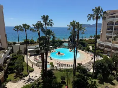 an aerial view of a pool with palm trees and the ocean at a 2 minutes de la plage vue mer et piscine in Cannes