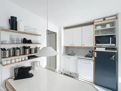 a kitchen with white cabinets and a black refrigerator at Appartement Cannes vue sur mer in Cannes